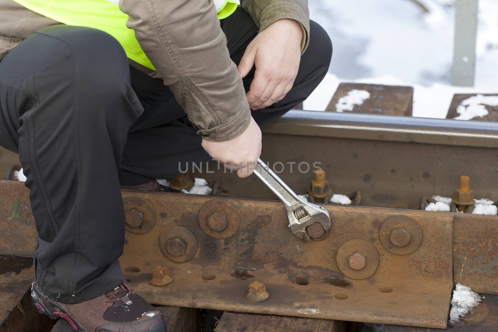 Railroad worker with wrench on the railway bridge fix the nut