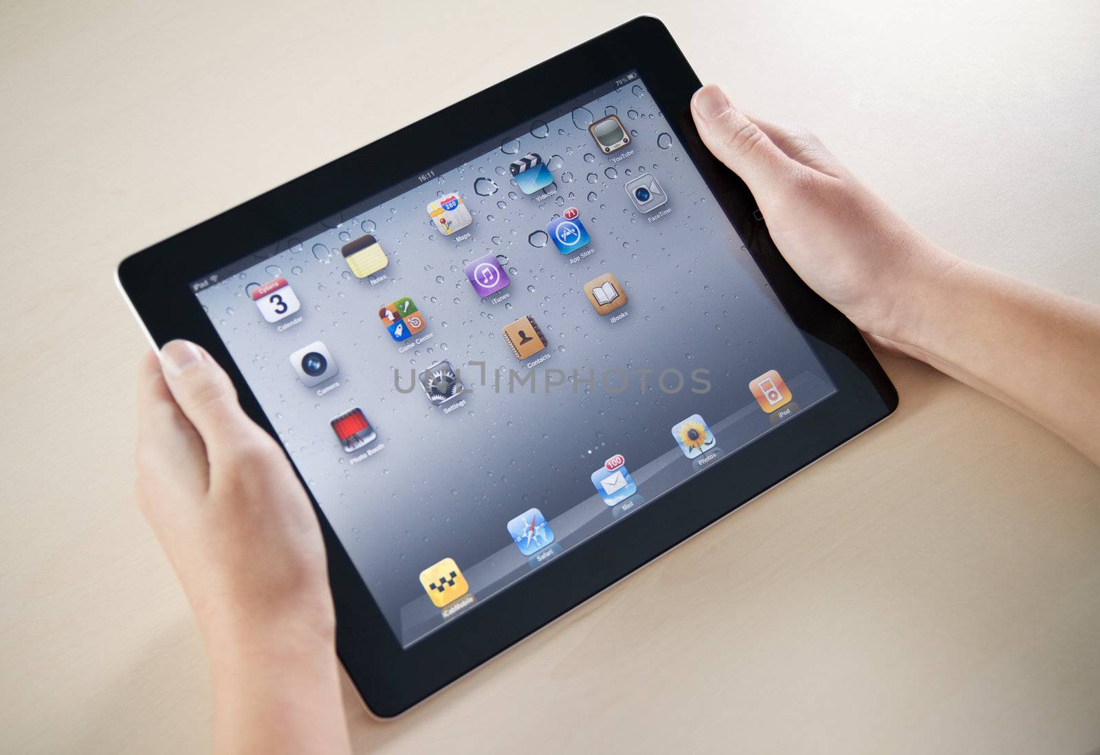 Kiev, Ukraine - December 03, 2011: Woman hands holding Apple iPad2 with homepage on a screen. This second generation Apple iPad2 is designed and development by Apple inc. and launched in march 2011.