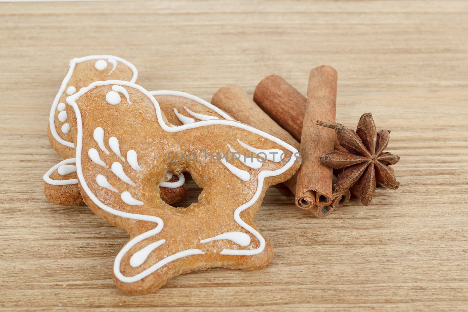 Gingerbread cookies birds hanging over wooden background with anise and cinamon