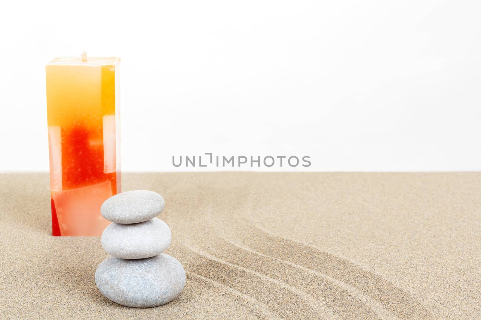 Balance zen stones and candle in sand on white background