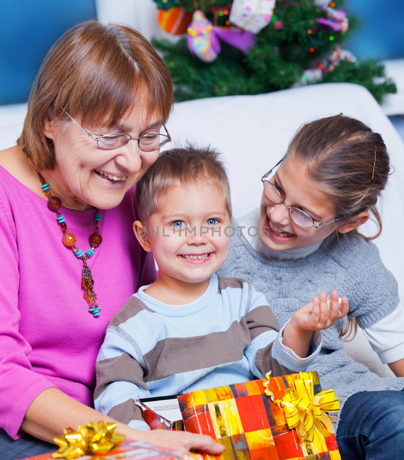 Cute Grandmother and her two grandchildren watching Christmas gifts