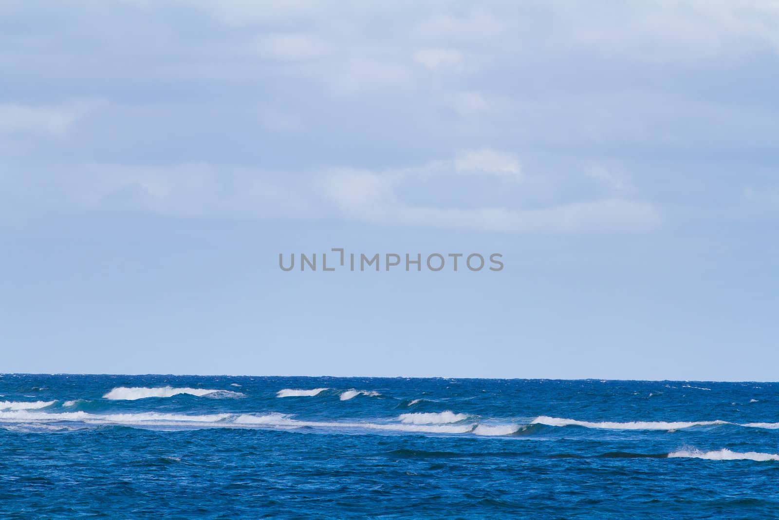 Blue water and a cloudy sky create this unique abstract landscape nature image of the Pacific Ocean. This is off the coast of the north shore of Oahu during a storm with rough water.