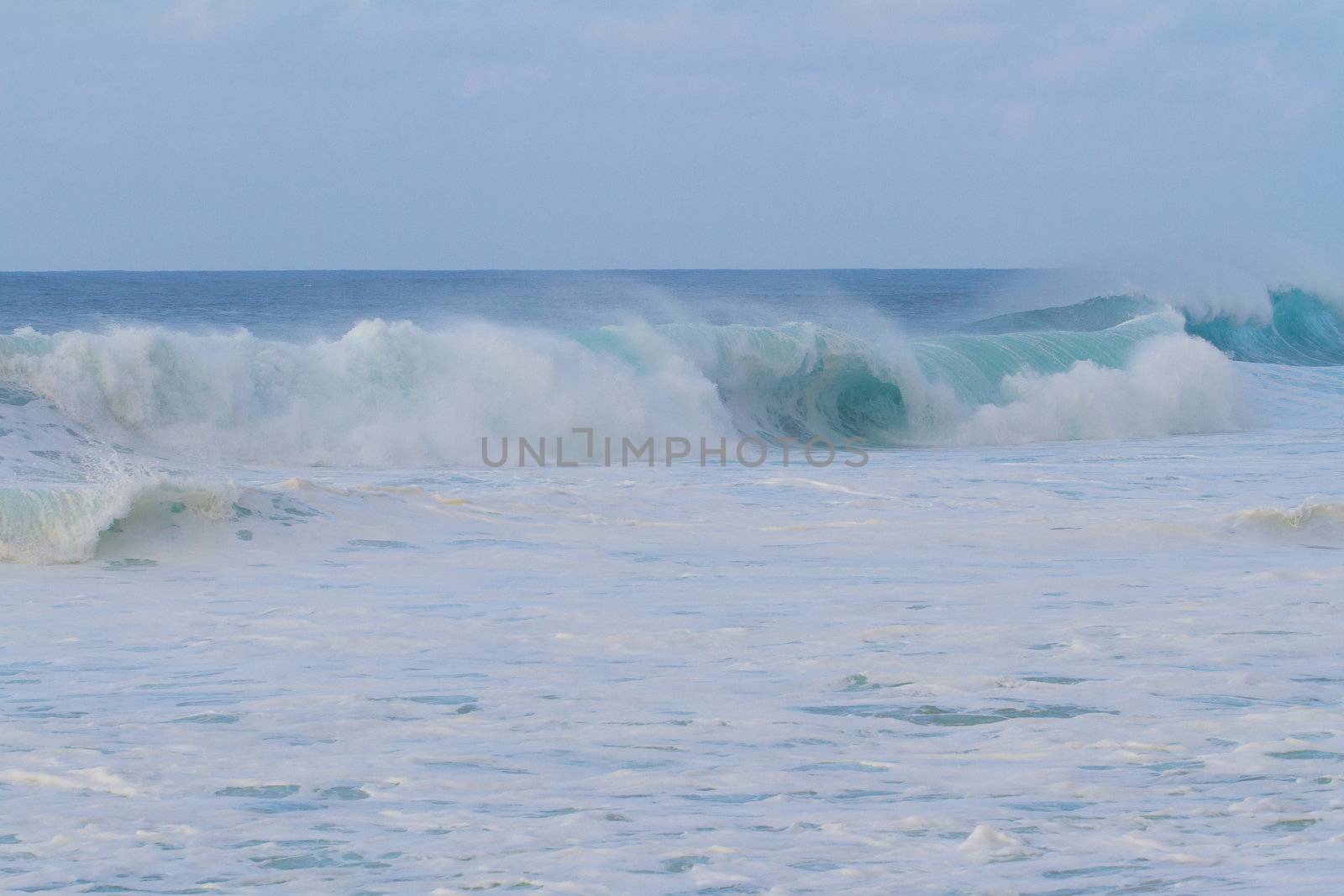 A giant wave breaking during a storm on the north shore of Oahu in Hawaii. These incredible waves have tons of white water and froth with hollow barrels and a dangerous rip current.