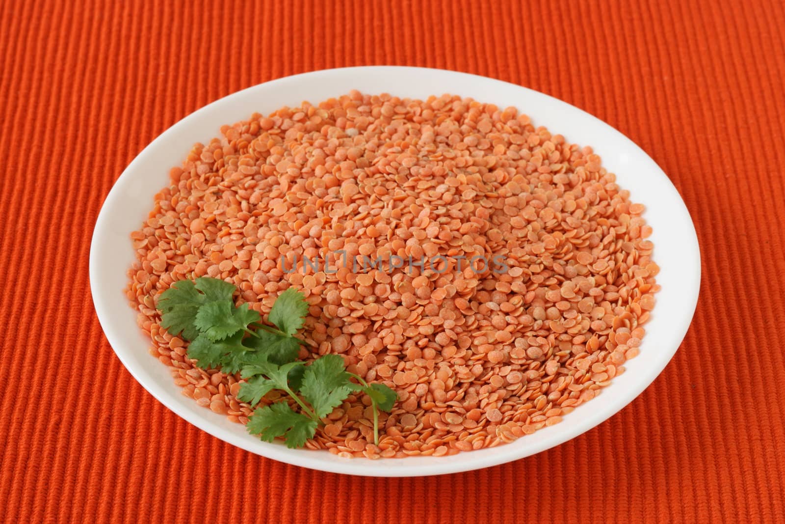 dry red lentil on the plate by nataliamylova