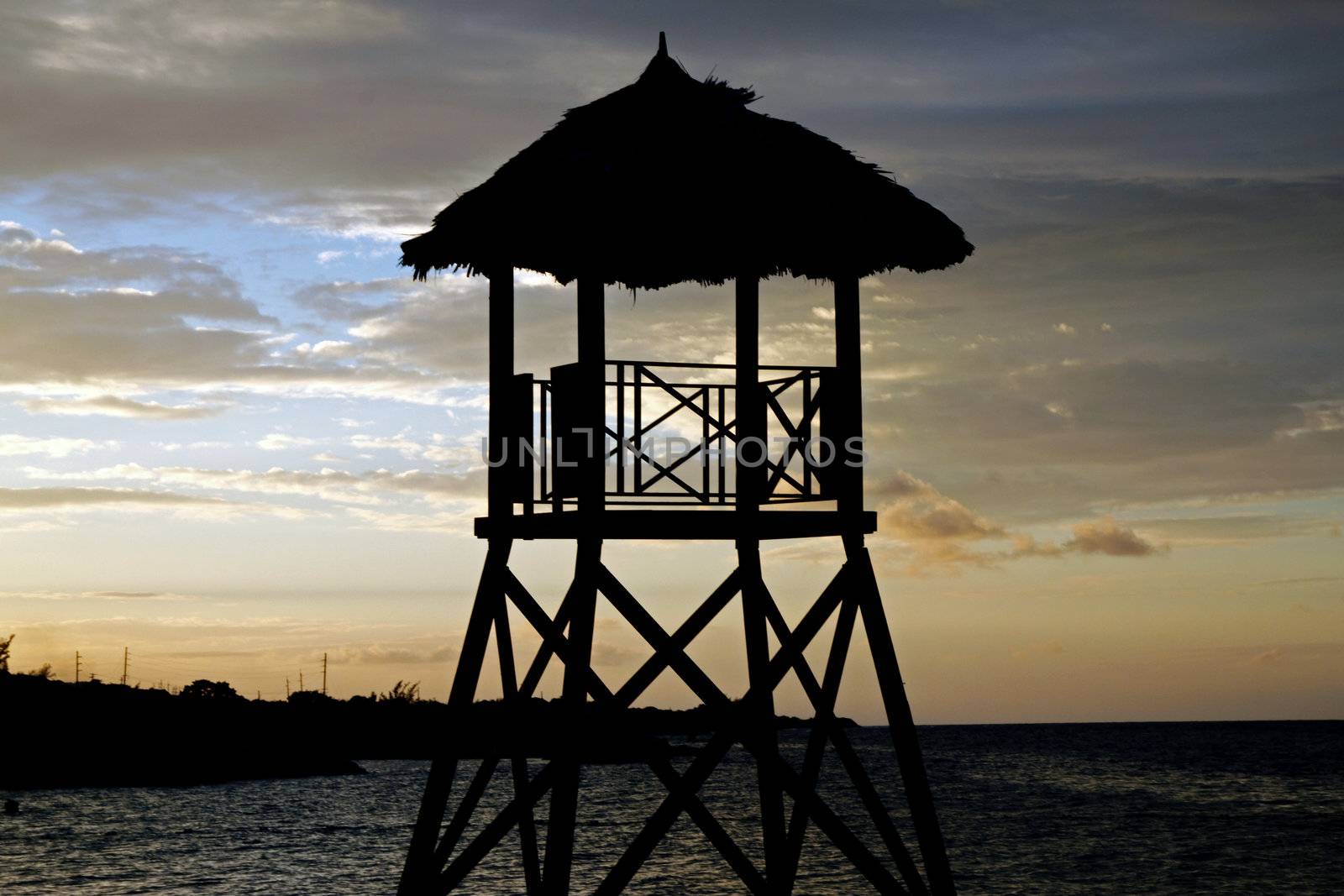 Tropical watchtower overlooking a beach silhouette at sunset