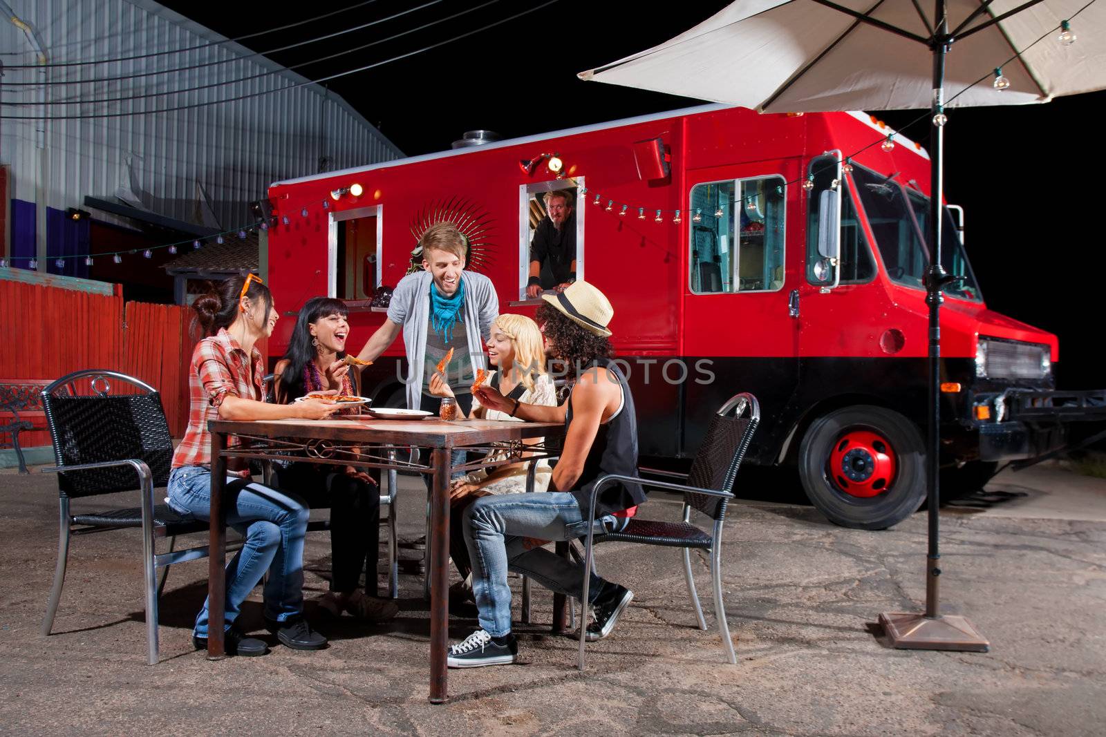 Laughing friends at food truck eating pizza slices