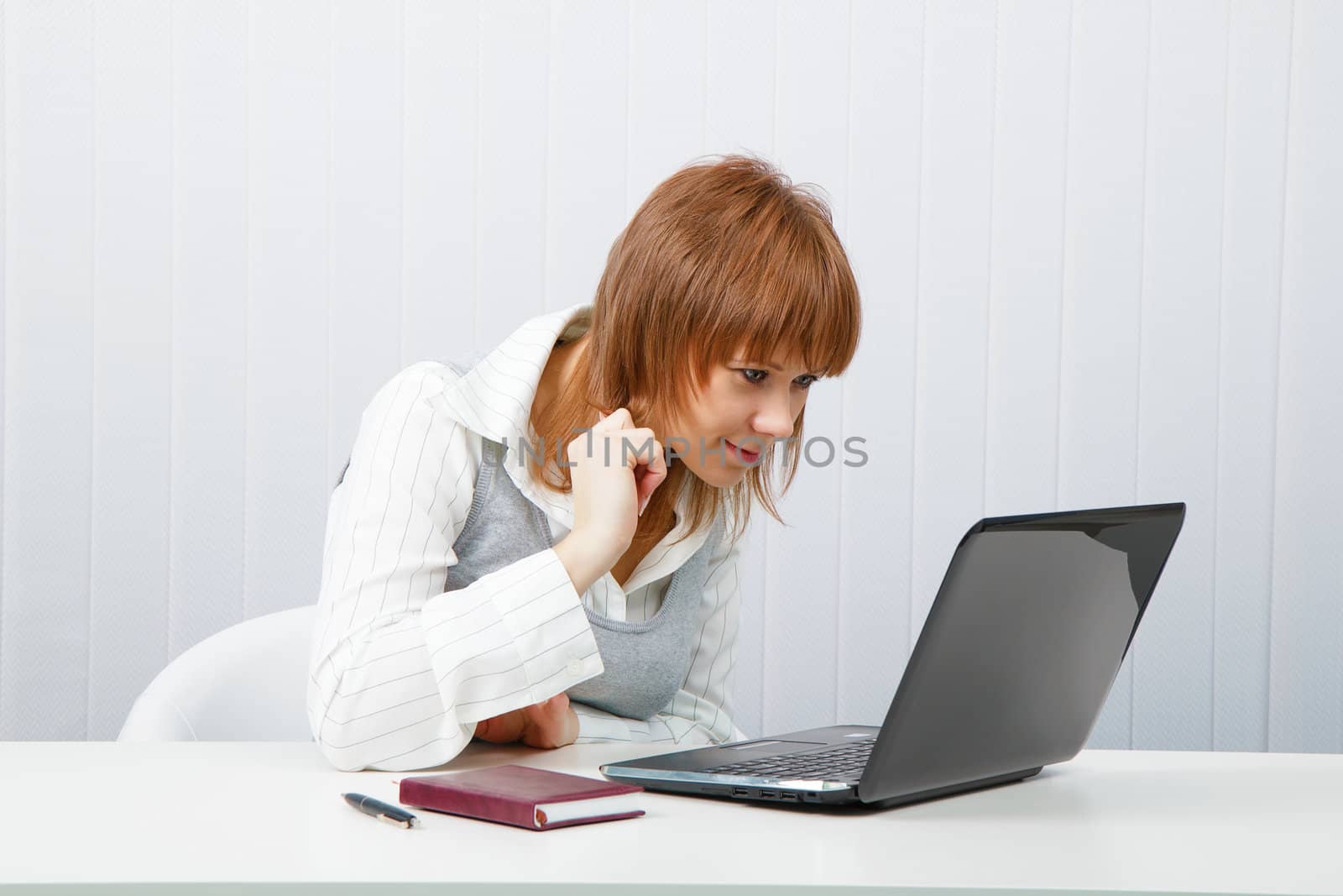 Attractive smiling girl with a laptop in the office
