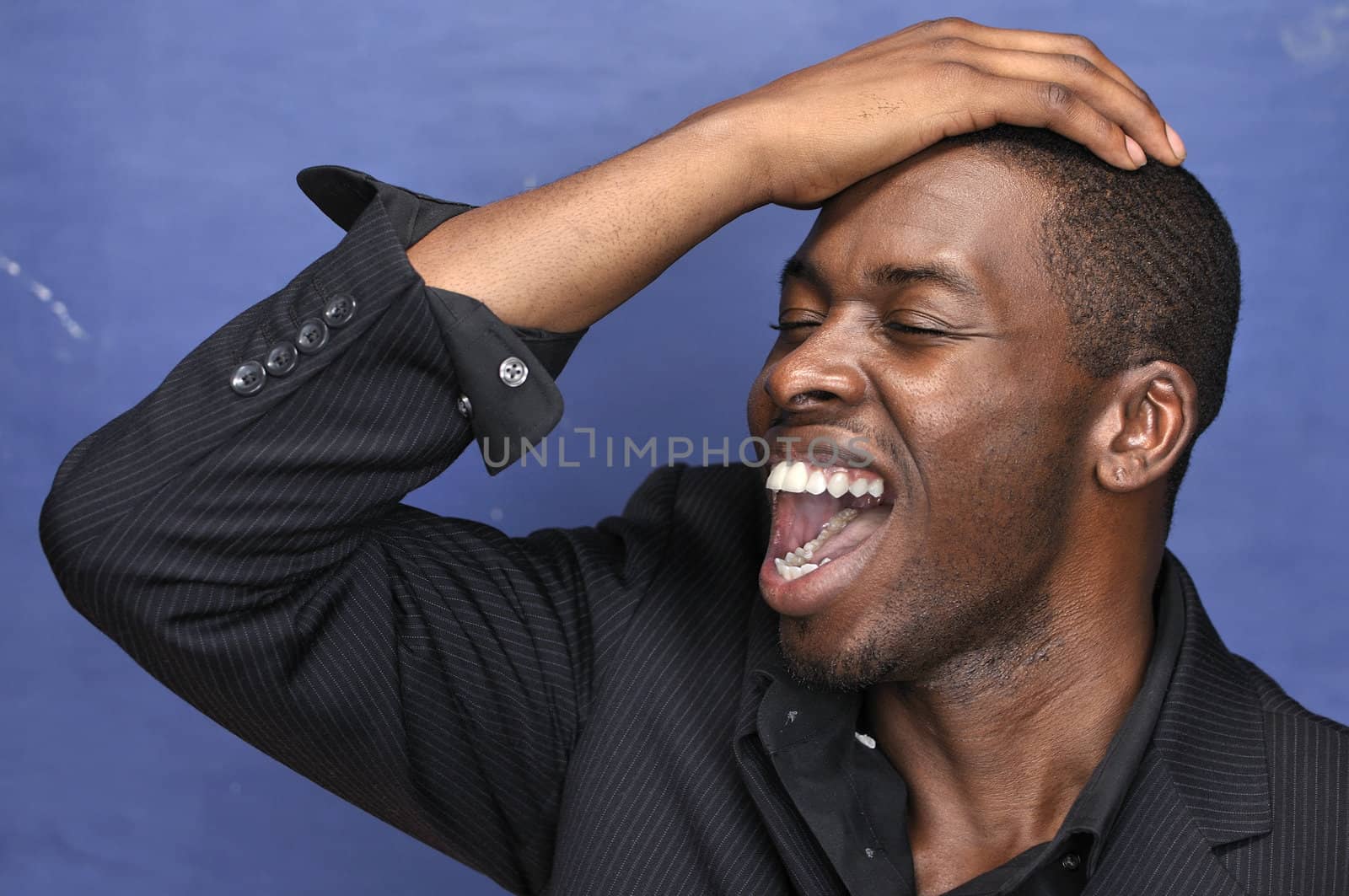 Young handsome black man in designer shirt yells with excitement on blue background