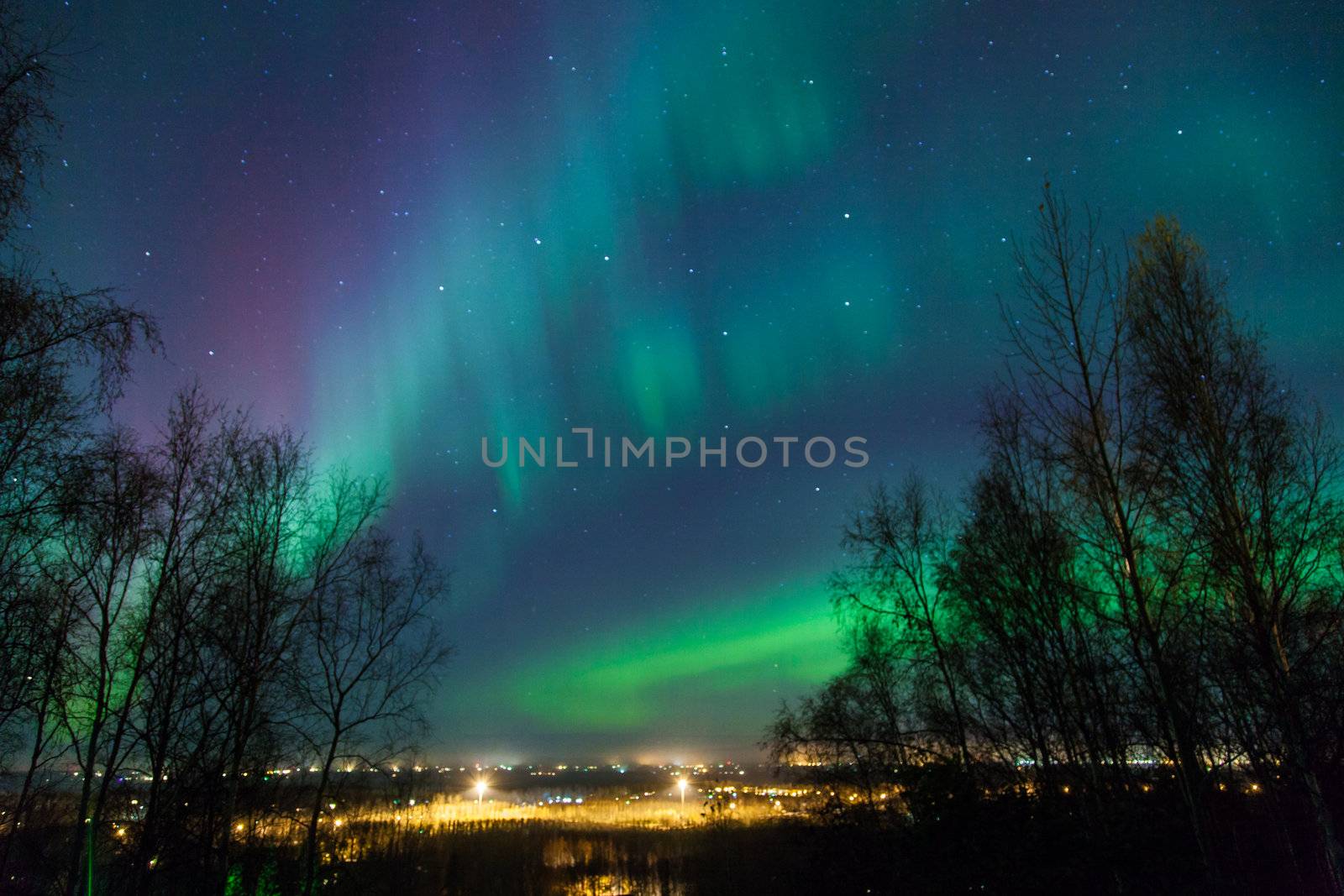 Northern lights and Big Dipper shine brightly over a city