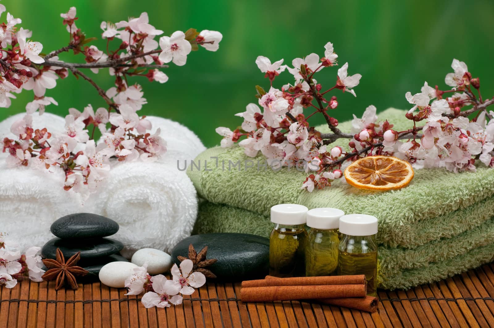 Spa concept with massage oils, cotton towels, aromatic spices, and healing pebbles