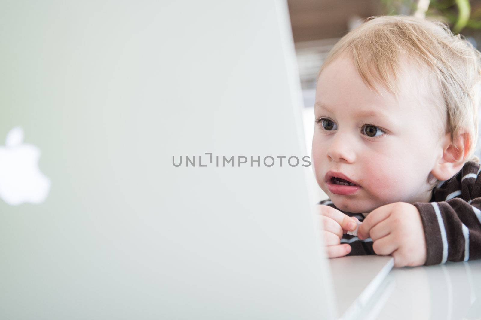 SALZBURG, JAN 23: Two years old Boy Lorenz, symbolic for the apple generation, looking at new apple macbook pro retina, on January 23 2013, in Salzburg, Austria