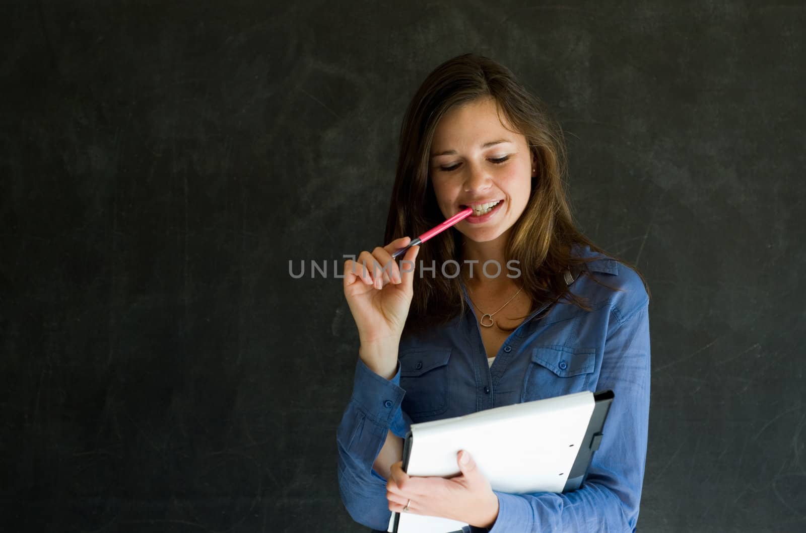 Confident woman with notepad and pen against a blackboard background