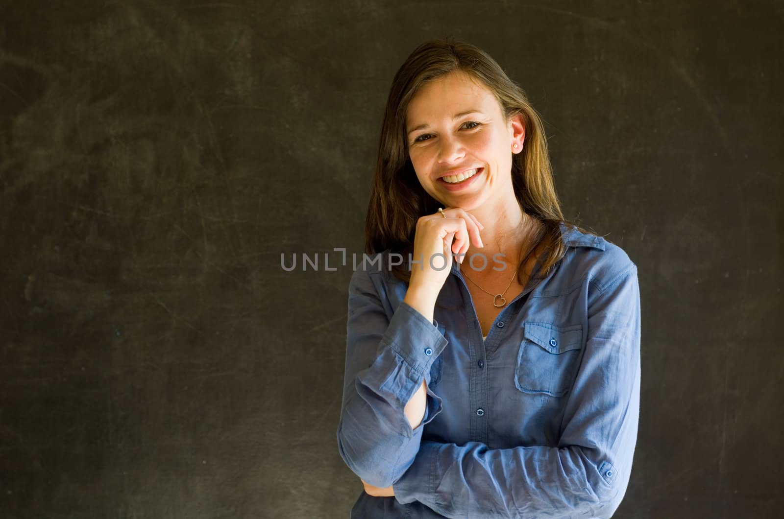 Confident woman with arms crossed against a blackboard background