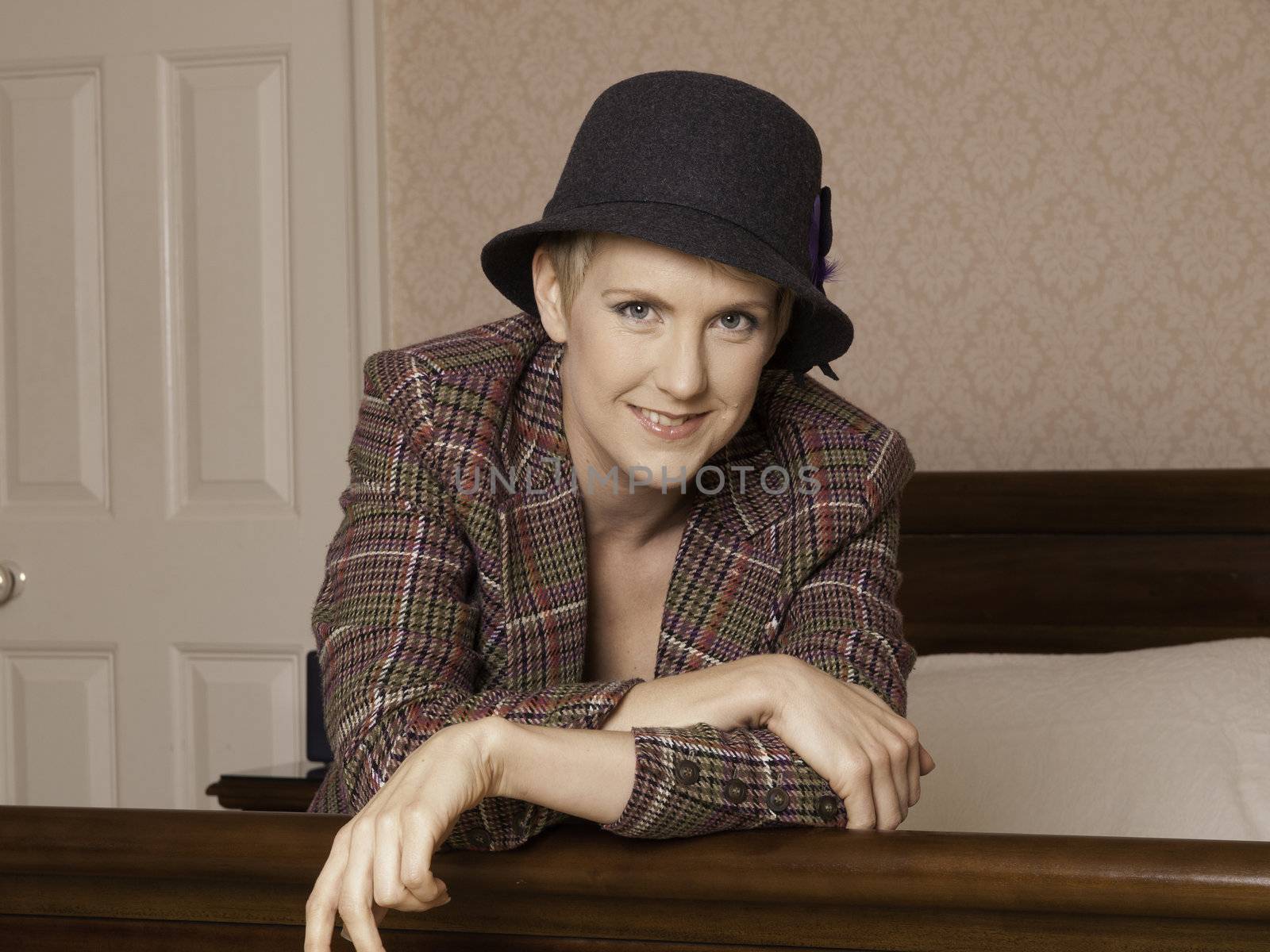 Woman in jacket, hat and lingerie on bed by ianthwaites