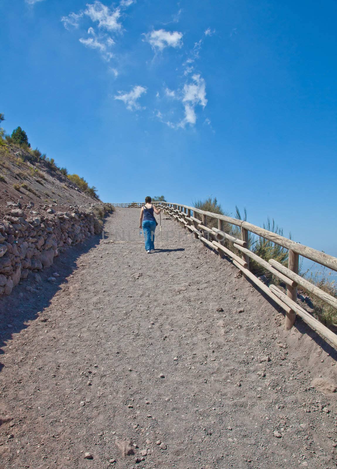 Lady walking for exercises during a sunny day on a mountain path