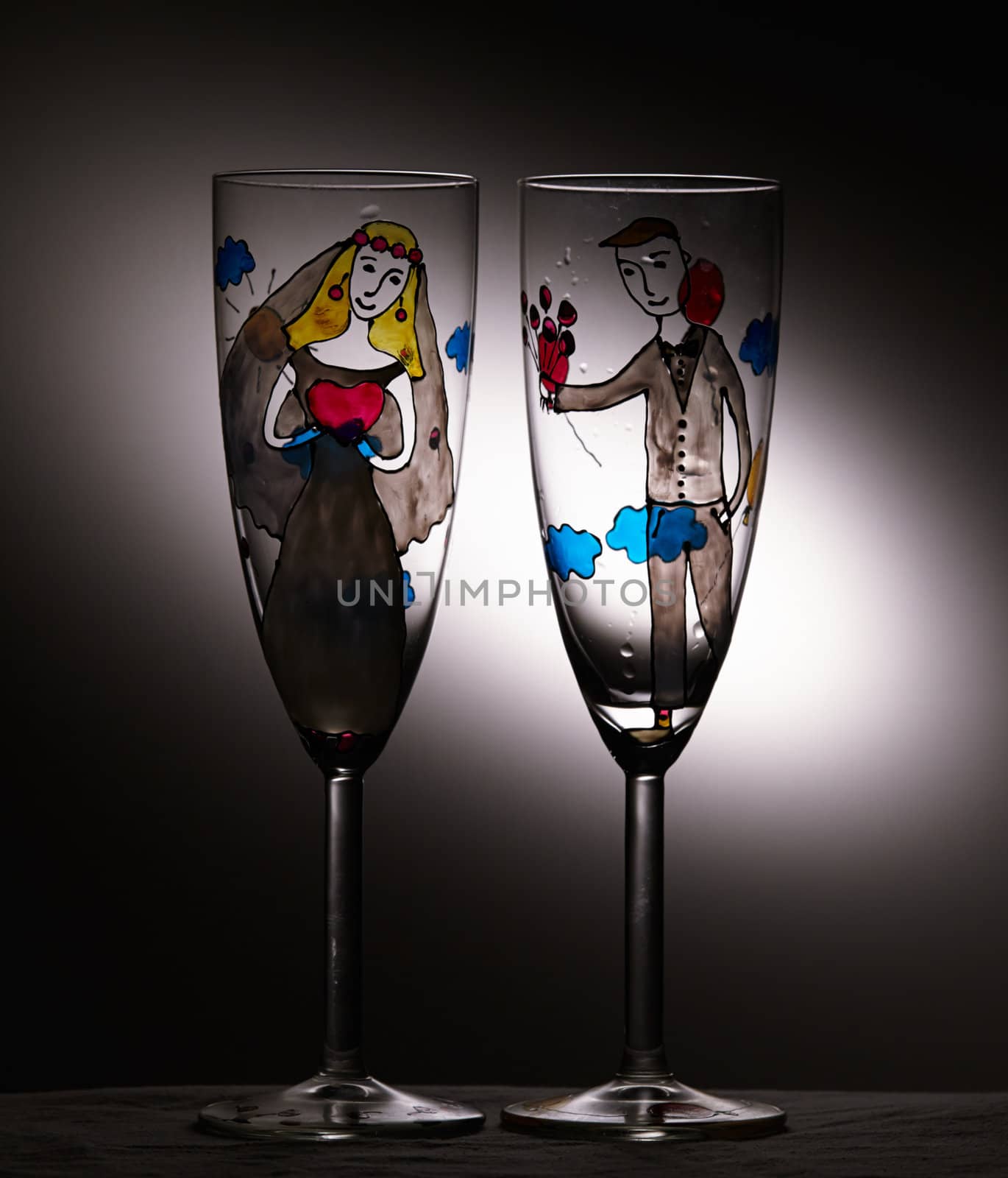 Vintage wedding empty champagne glasses on black background with light spot.