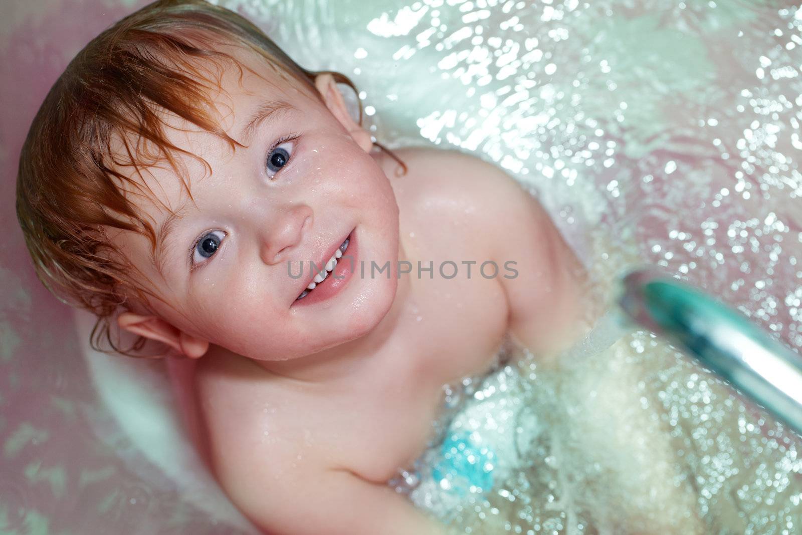 Closeup portrait of the little 2 year old boy taking a bath.