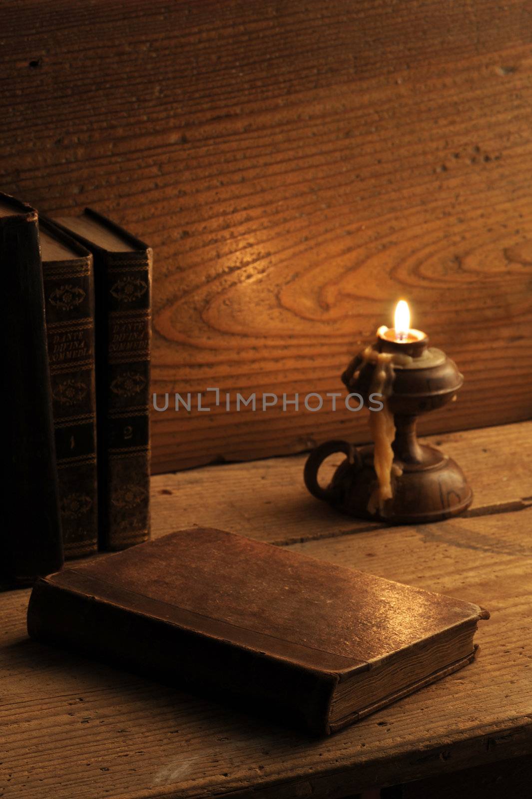 old book on a wooden table by candlelight by stokkete