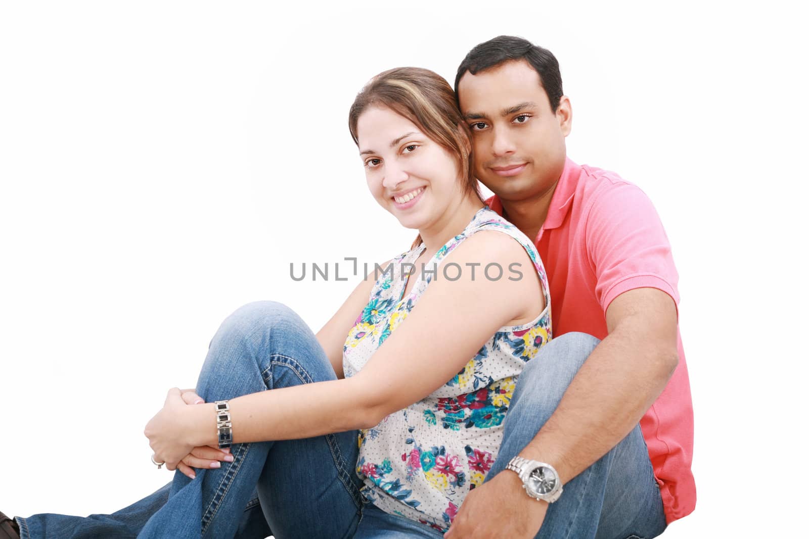 smiling happy couple sitting down next to wall