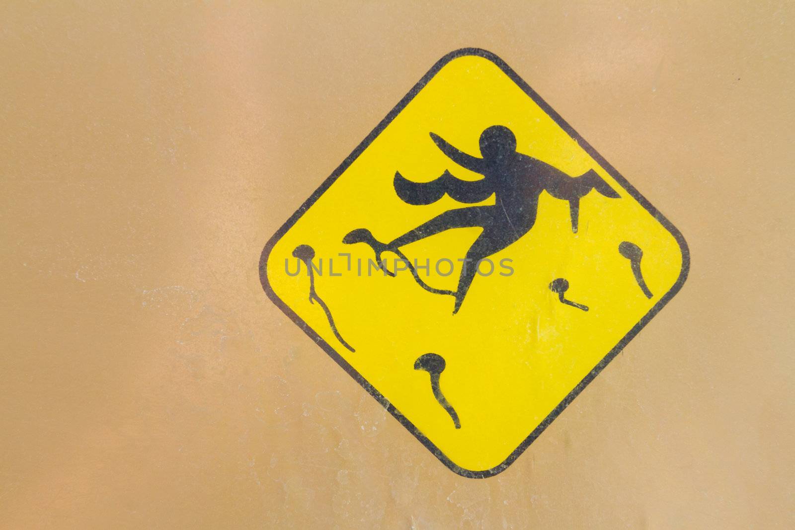 A yellow and black caution sign shows jelly fish stinging a person in the water and waves.