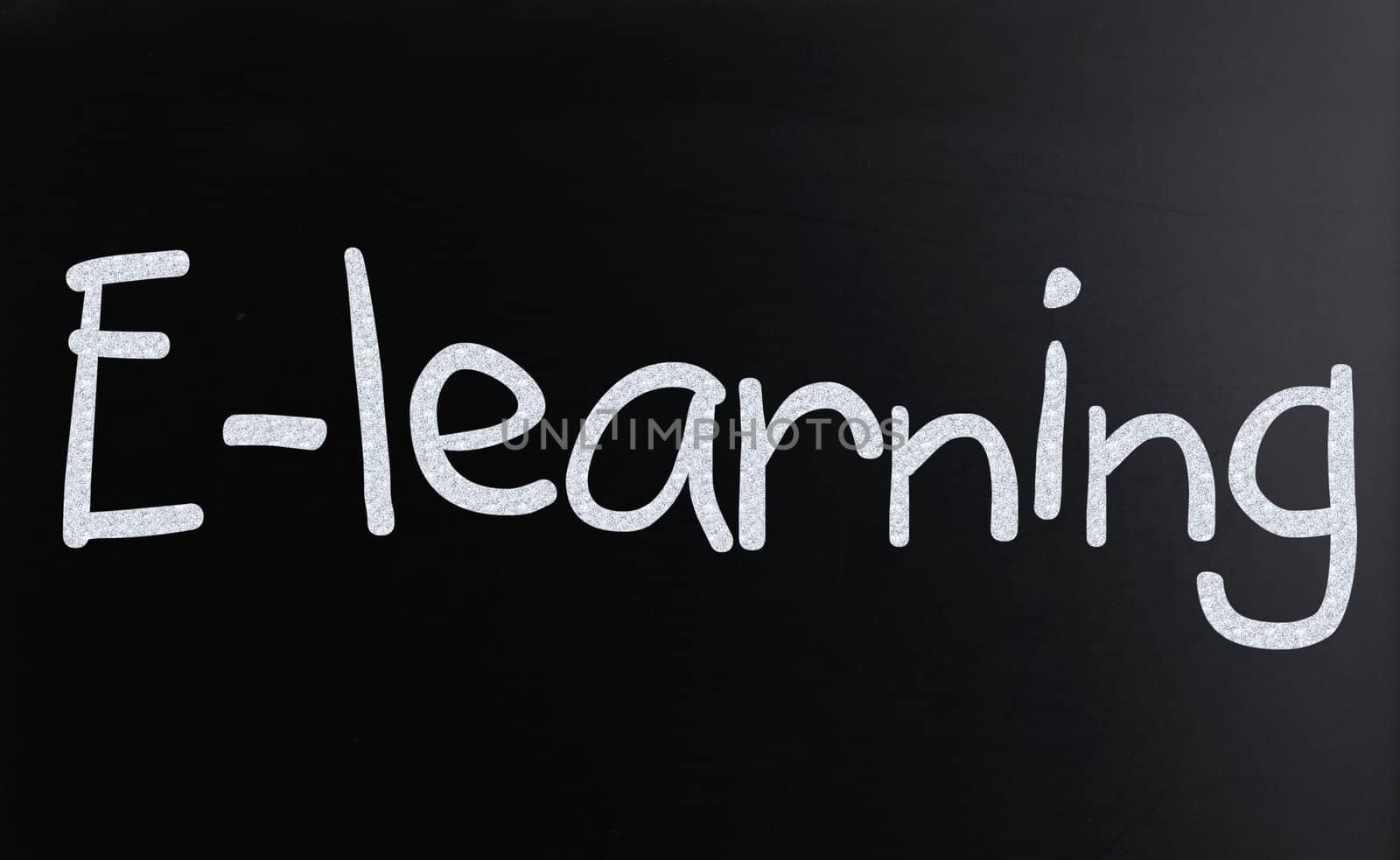 The word "E-learning" handwritten with white chalk on a blackboard
