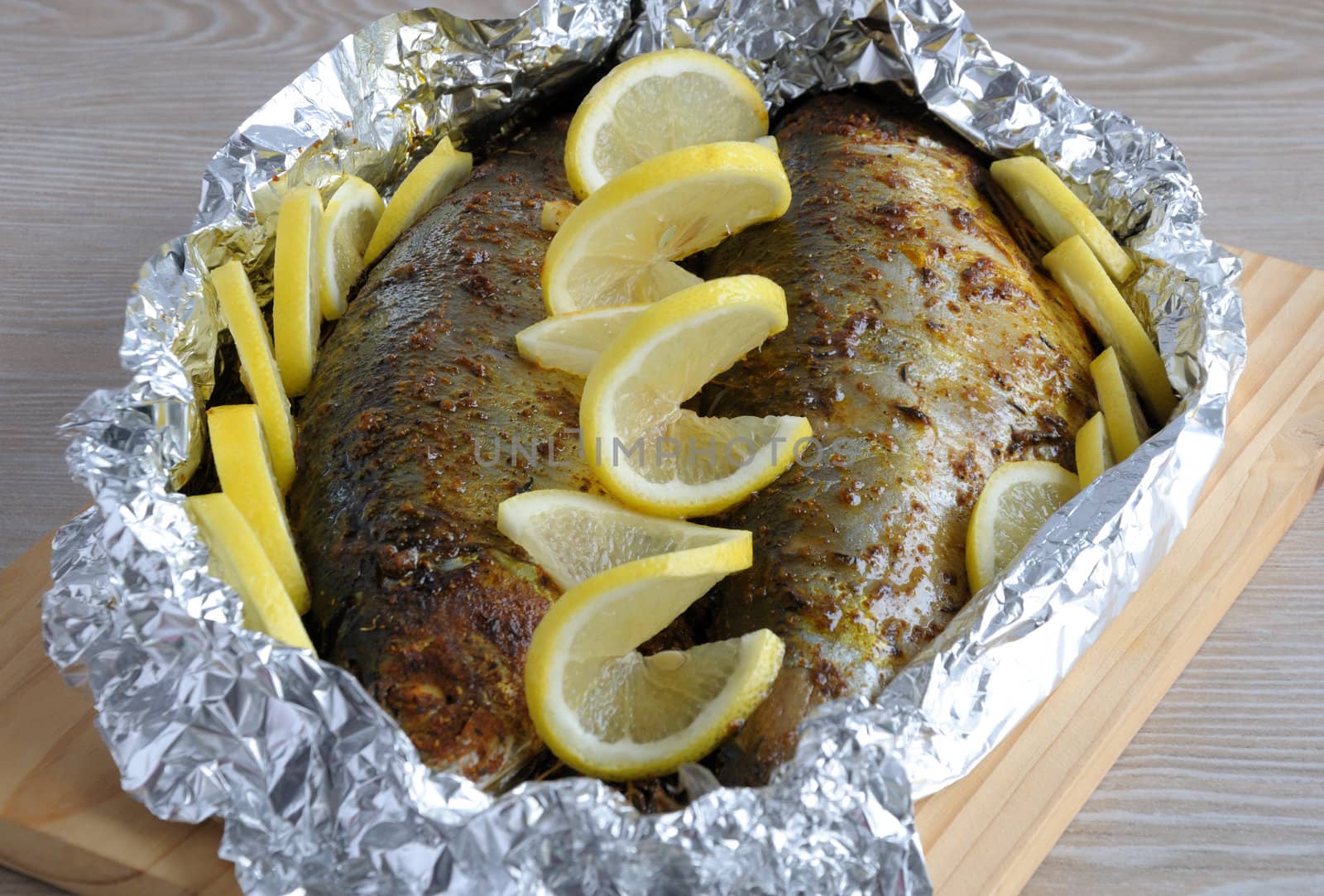 Baked herring in spices and herbs in foil with lemon