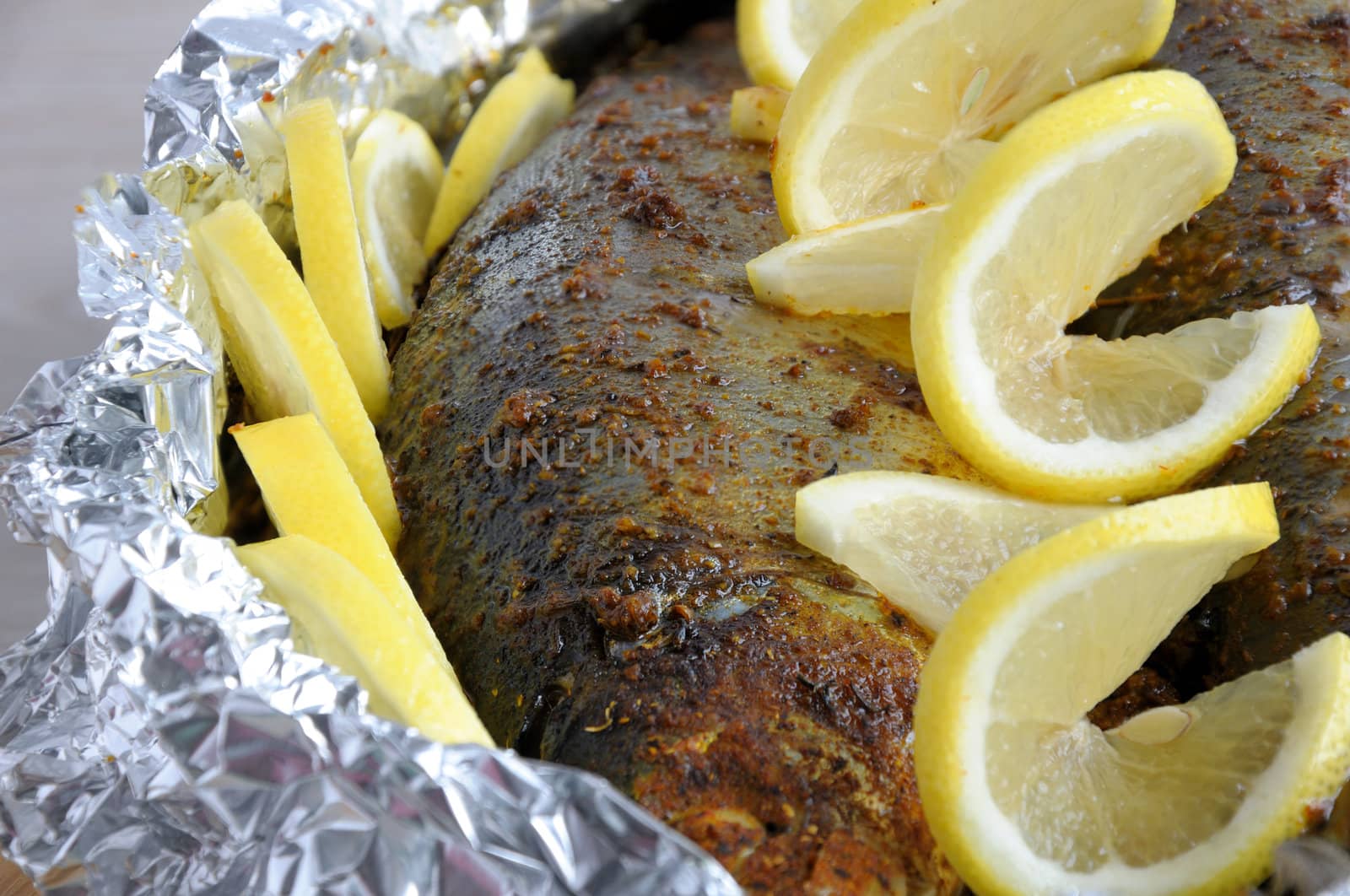 Baked herring in spices and herbs in foil with lemon