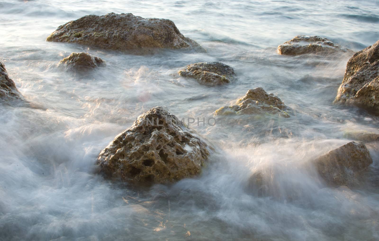 stones in sea water washing by waves, long exposure