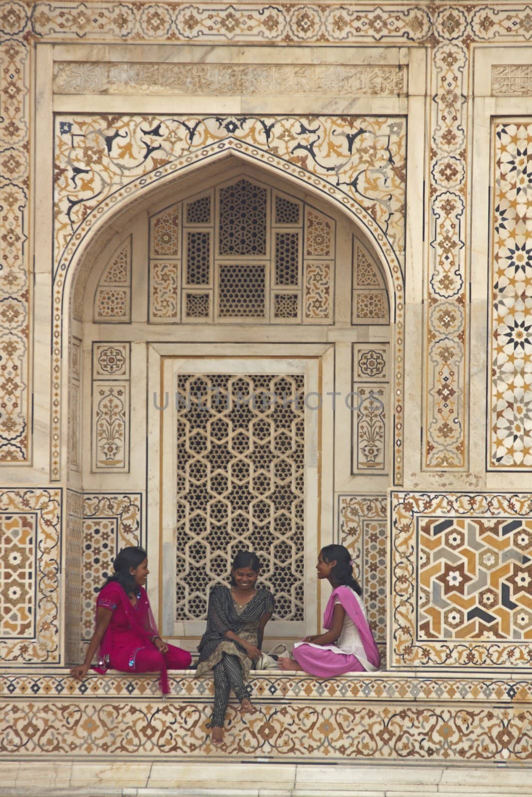 Indian teens in colorful sari's sitting in the alcove of a beautiful Mughal Tomb, I'timad-ud-Daulah in Agra, Uttar Pradesh, India