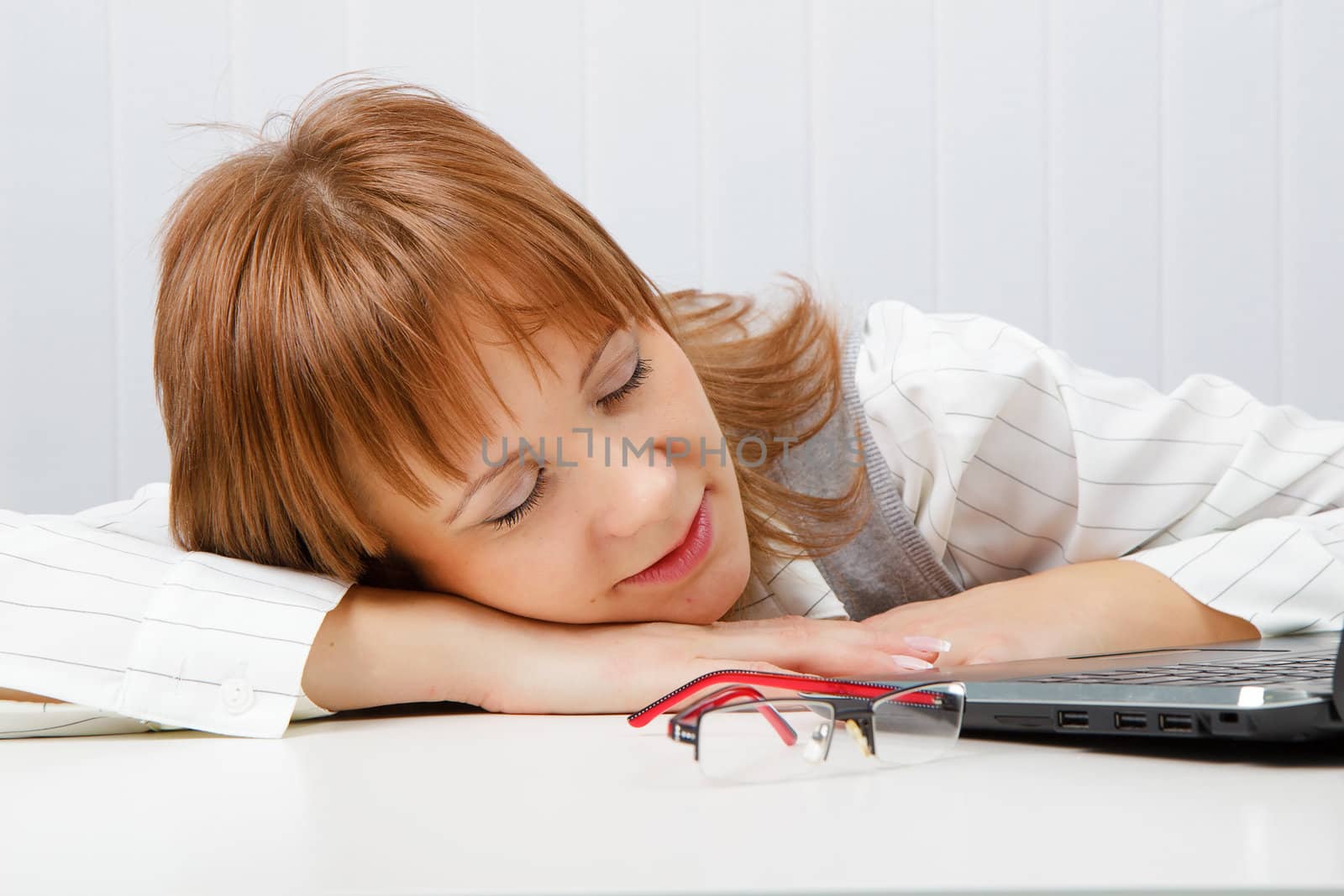 Tired girl lies on a table with a laptop