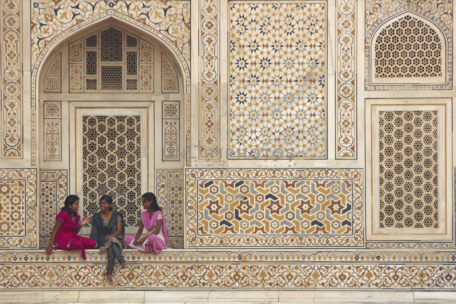 Indian teens in colorful sari's sitting in the alcove of a beautiful Mughal Tomb, I'timad-ud-Daulah in Agra, Uttar Pradesh, India