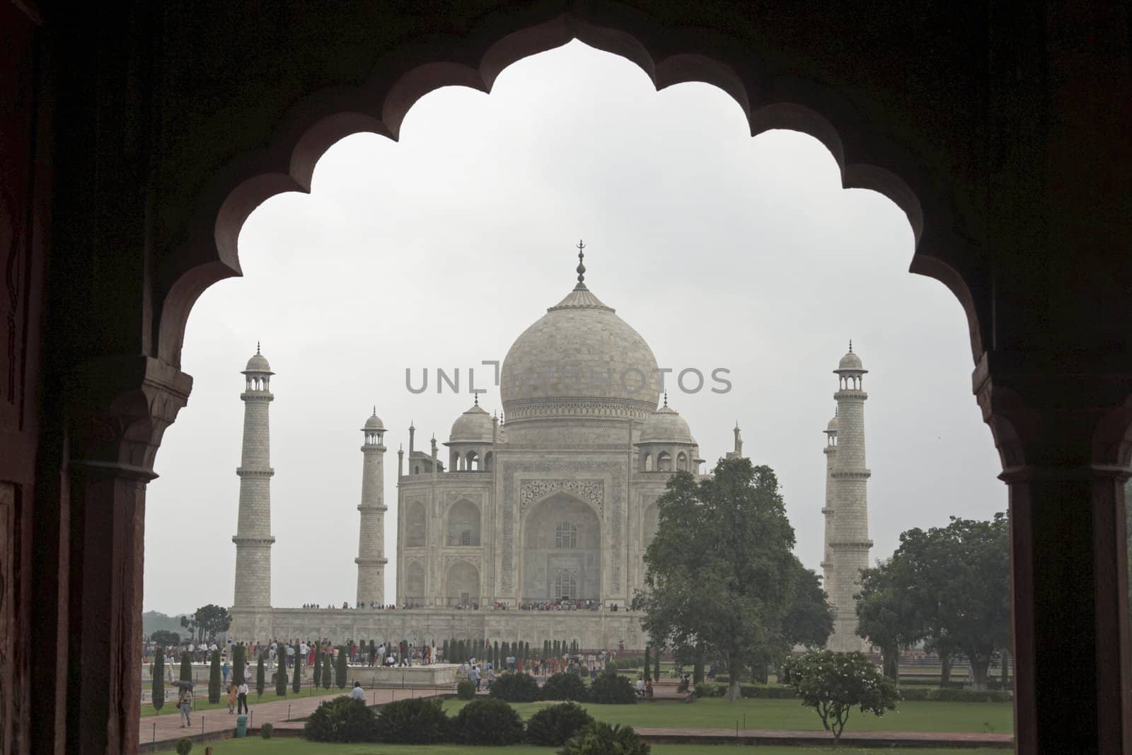 Taj Mahal. White marble tomb set on raised platform topped by large oval dome. Framed in Mughal arch. Agra, Uttar Pradesh. India