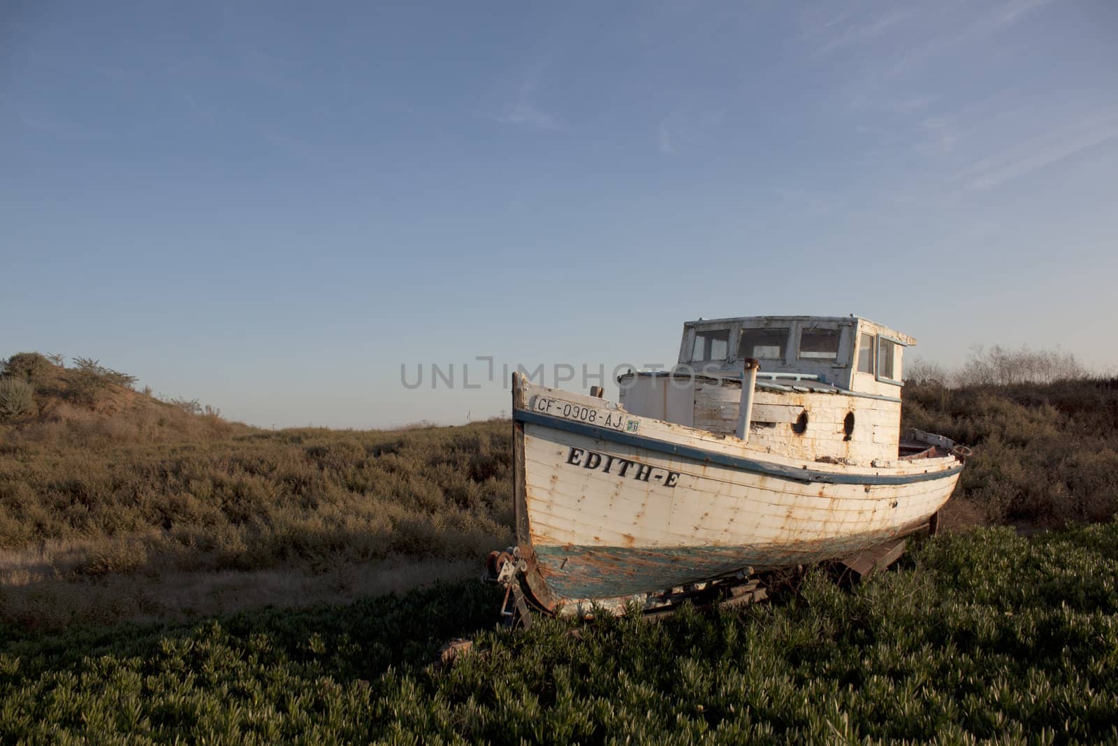 an old abandoned boat out of water with a blue sky.