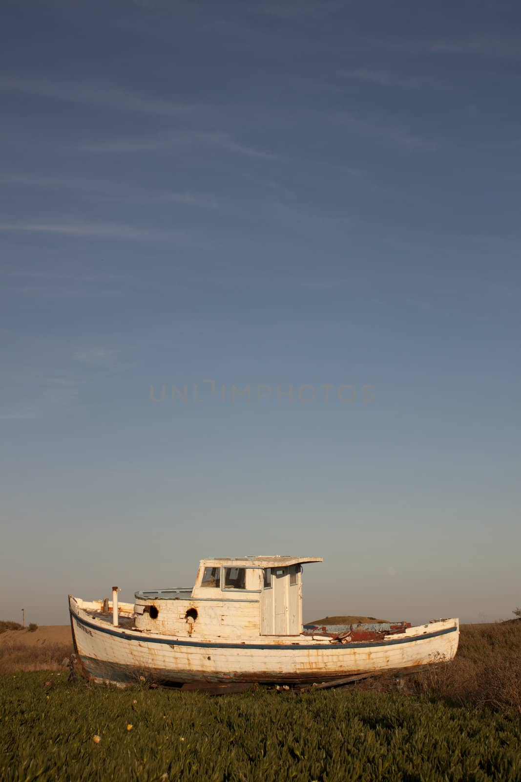 an old abandoned boat out of water with a blue sky.