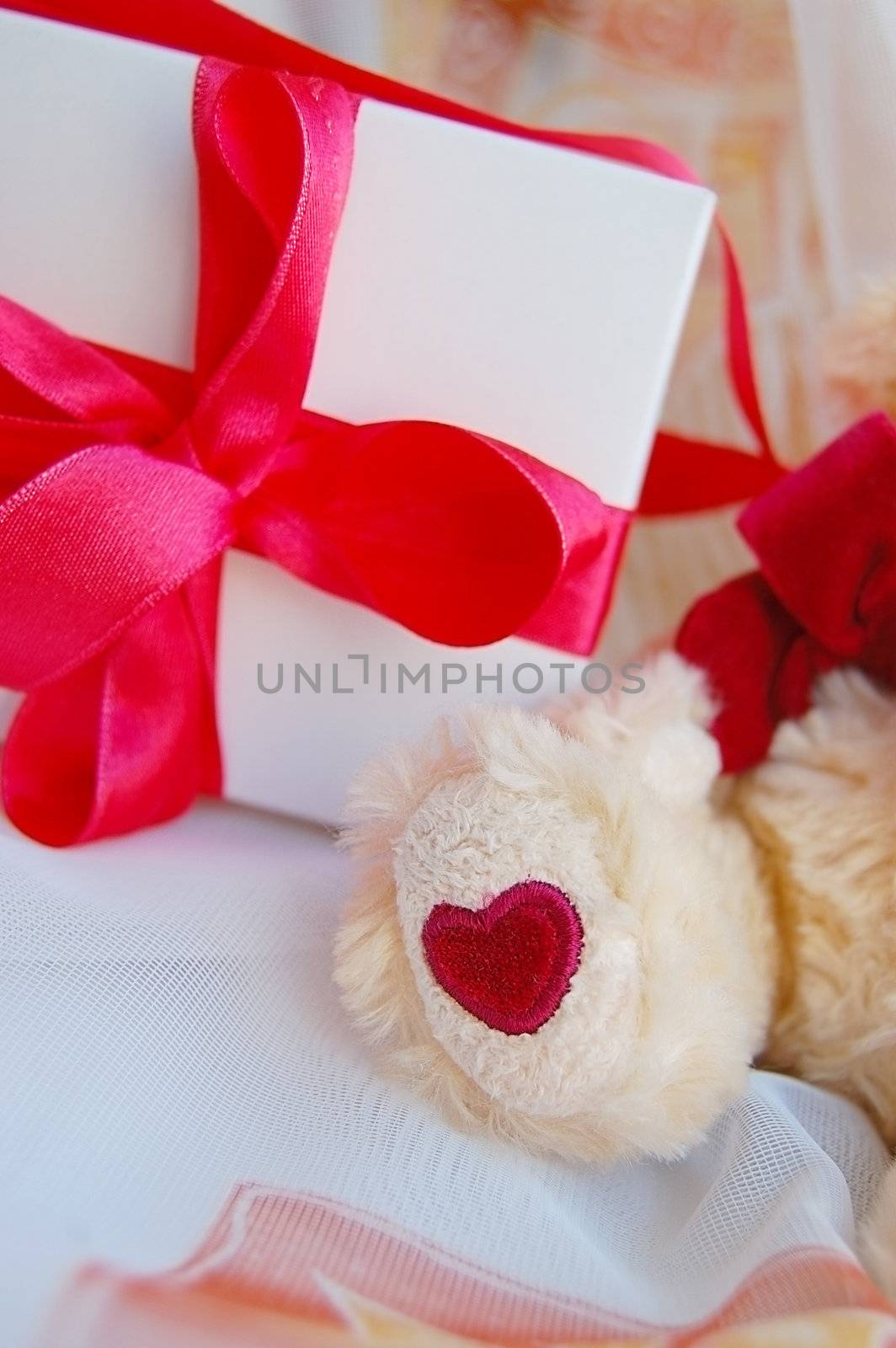 Gift box with red ribbon and teddy bear foot
