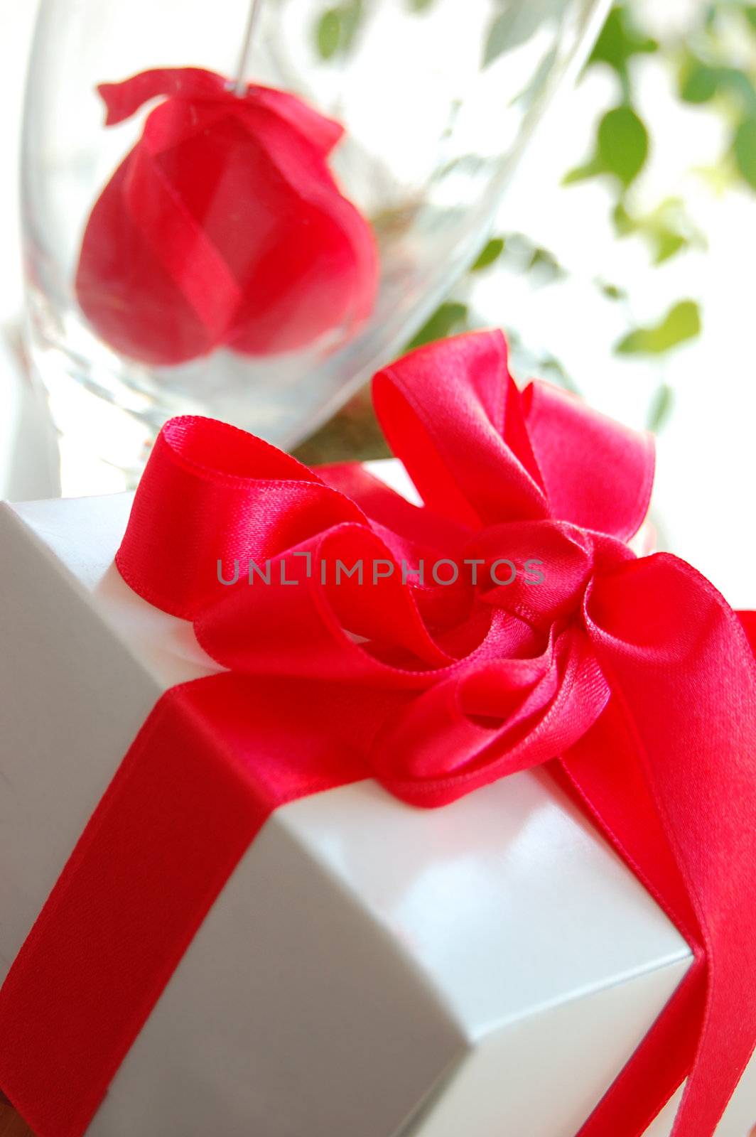 Gift box with red ribbon and fabric heart inside glass