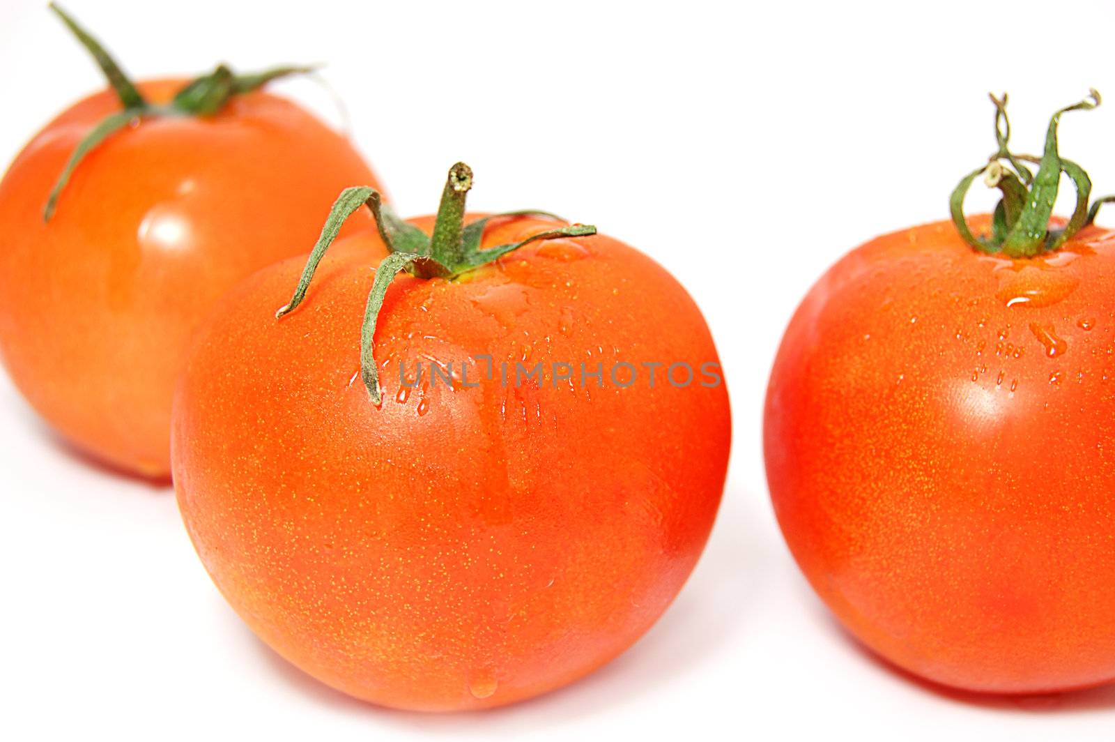 Three ripe red tomatos with green ends isolated on white