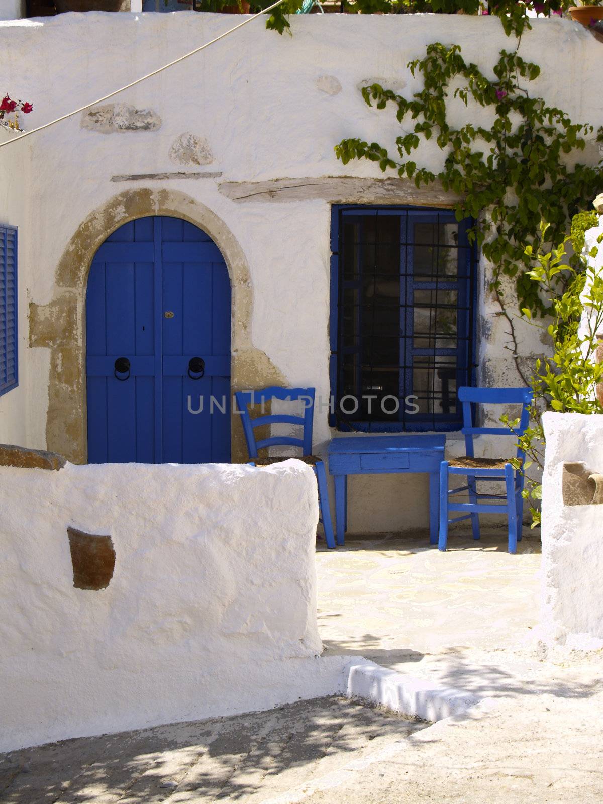 table and two chairs in front of an old greek house