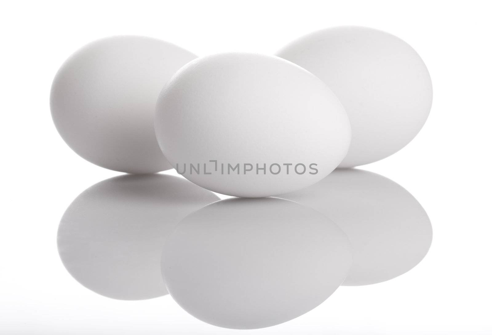 Three white eggs and their reflection