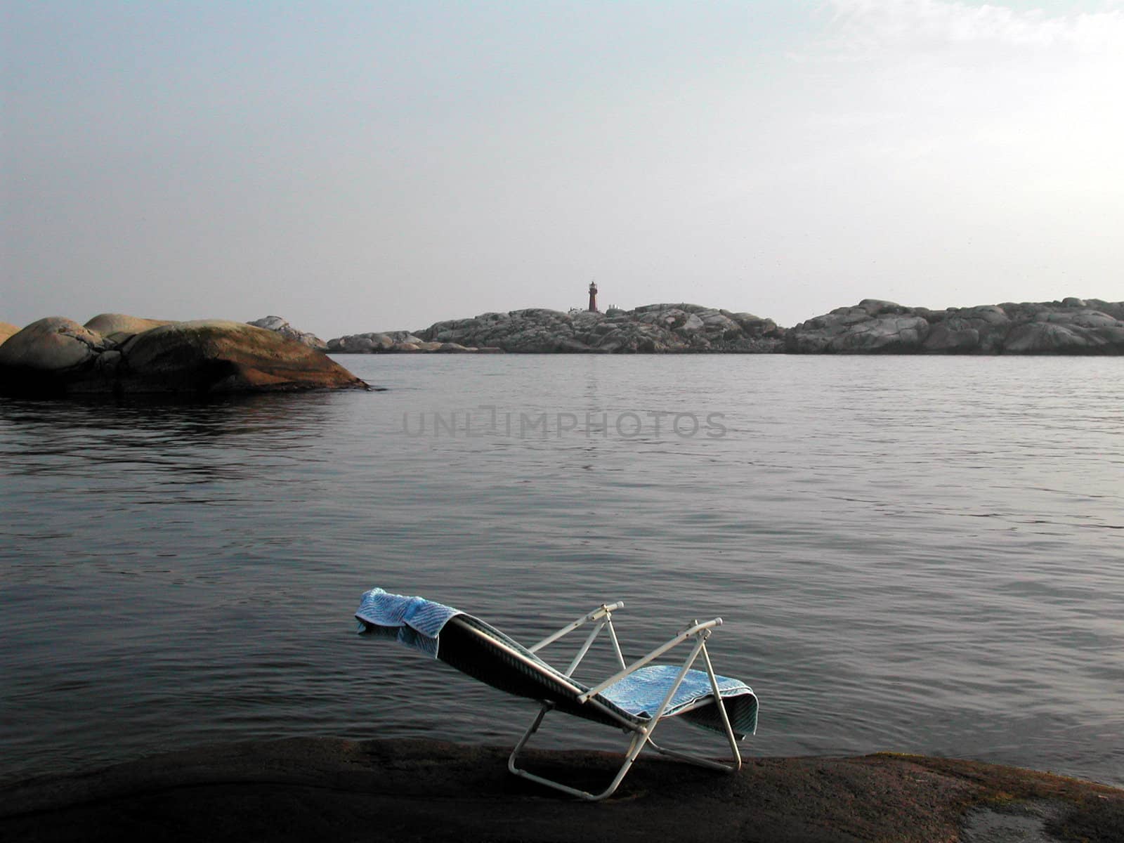 Lonely chair in Norwegian coastline.
Svenner lighthouse in background. 