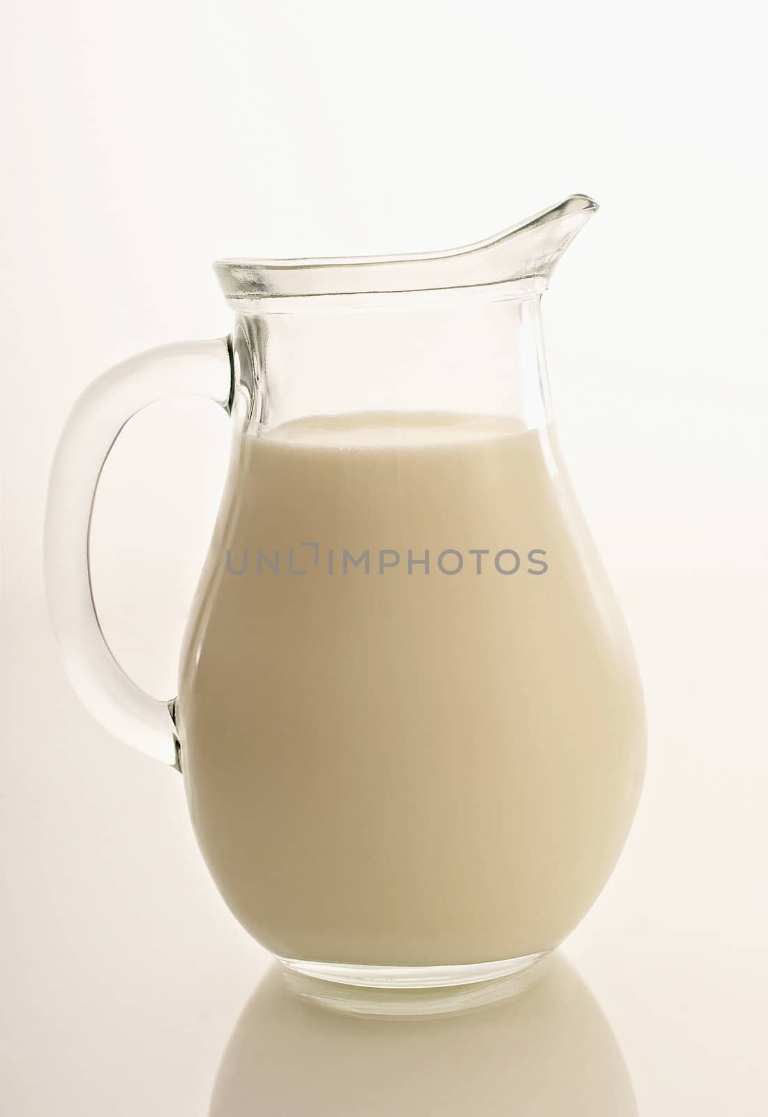 Glass jug with milk on white by ozaiachin