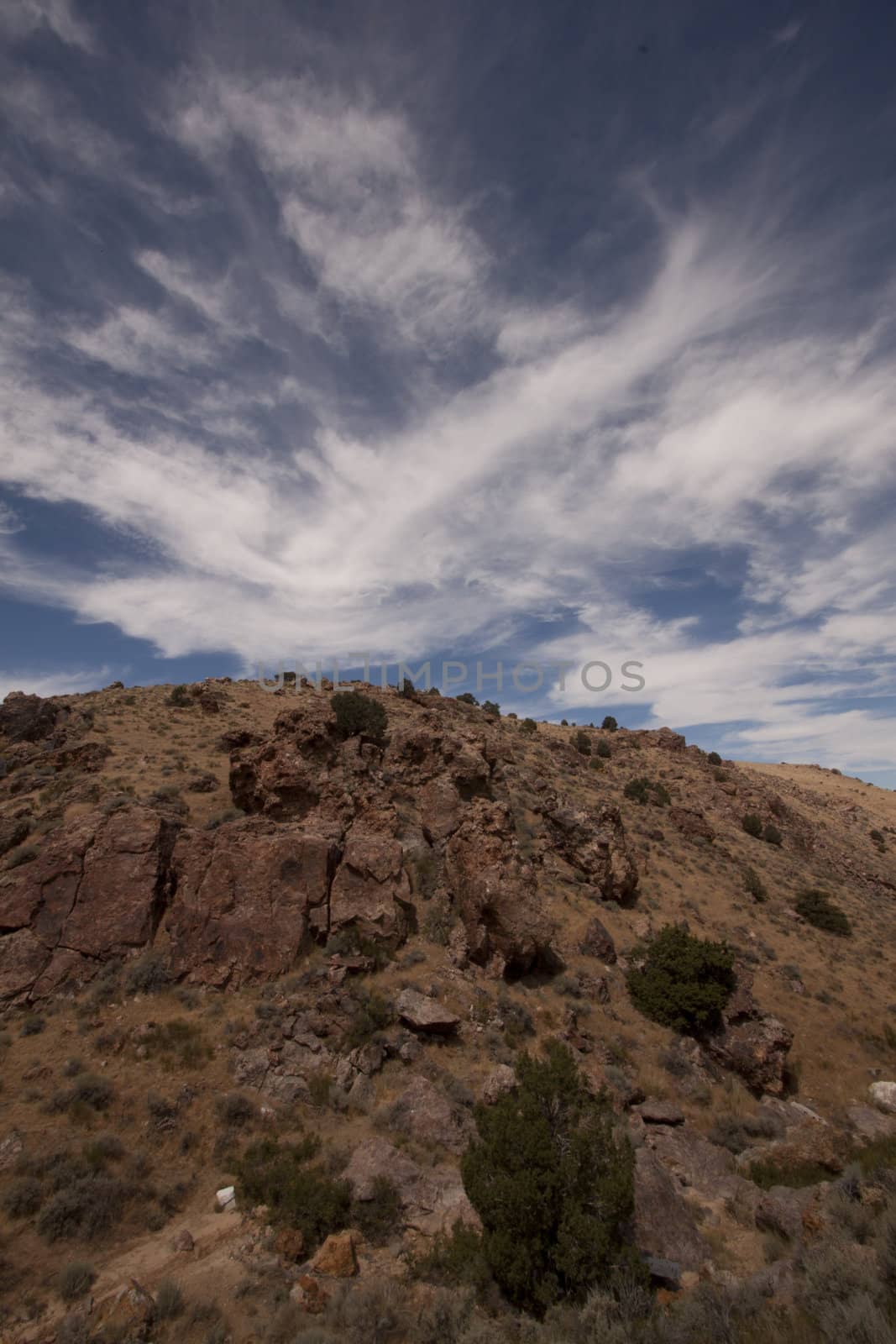 High deset rocky hillside with blue sky and beautiful couds by jeremywhat