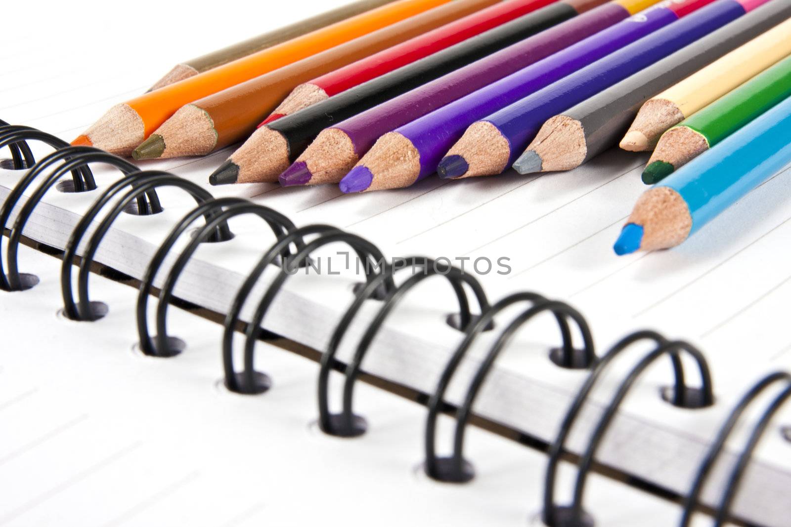 Color pencils in arrange in color wheel colors on note book with copy space