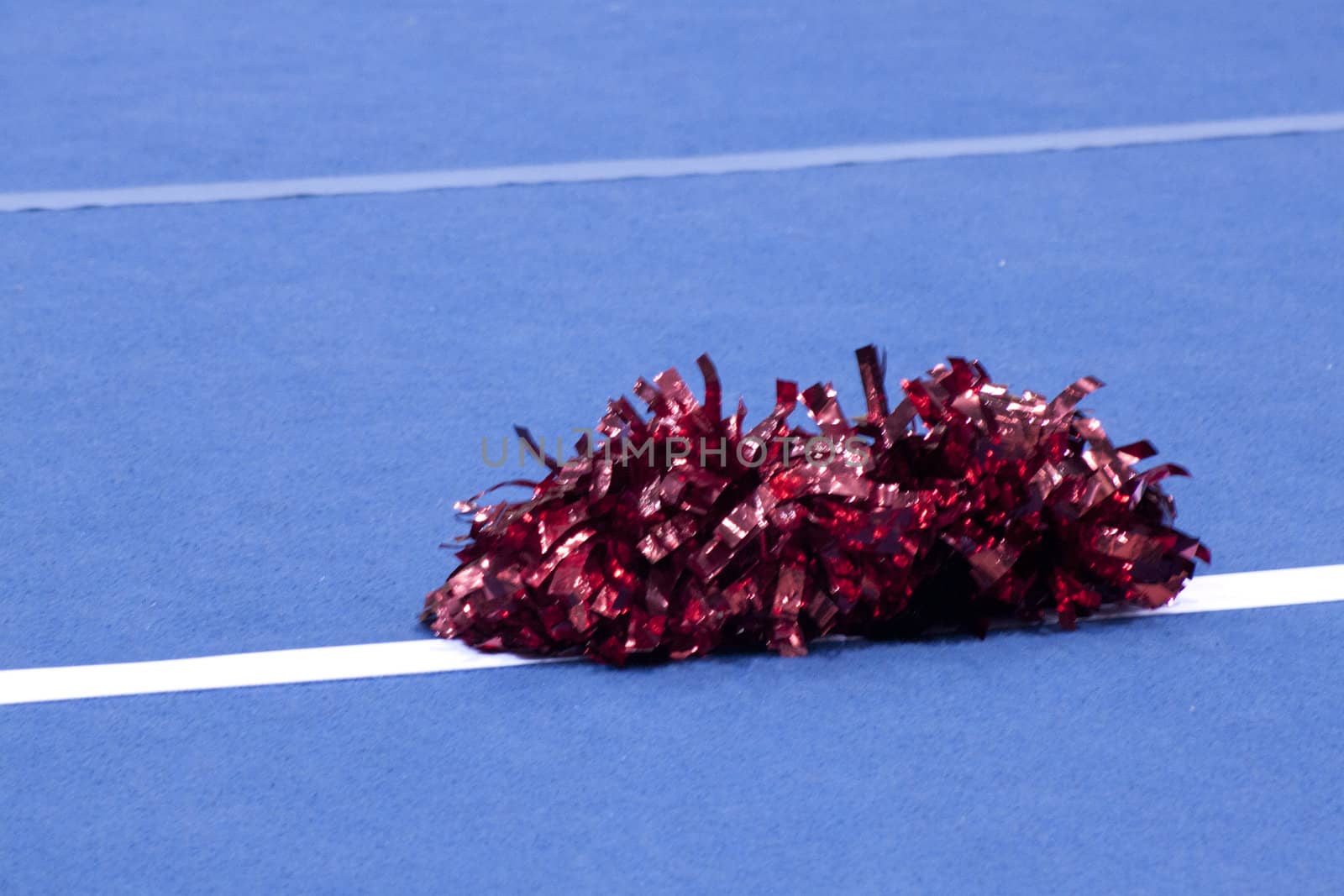 Cheerleading compitition pom poms on a blue mat with lines.