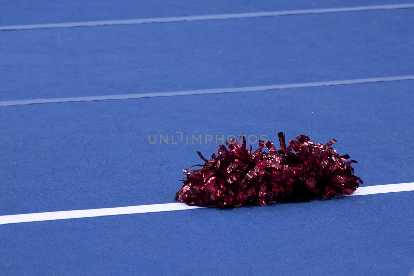 Cheerleading compitition pom poms on a blue mat with lines.