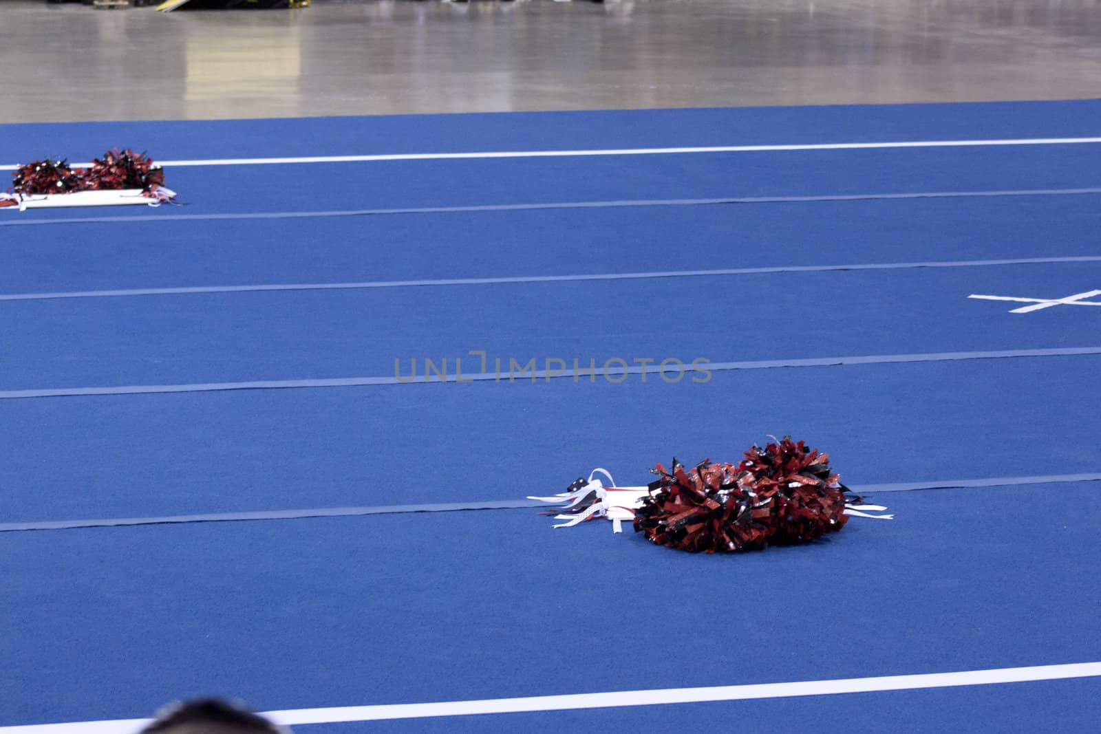 Cheerleading compitition pom poms on a blue mat with lines.
