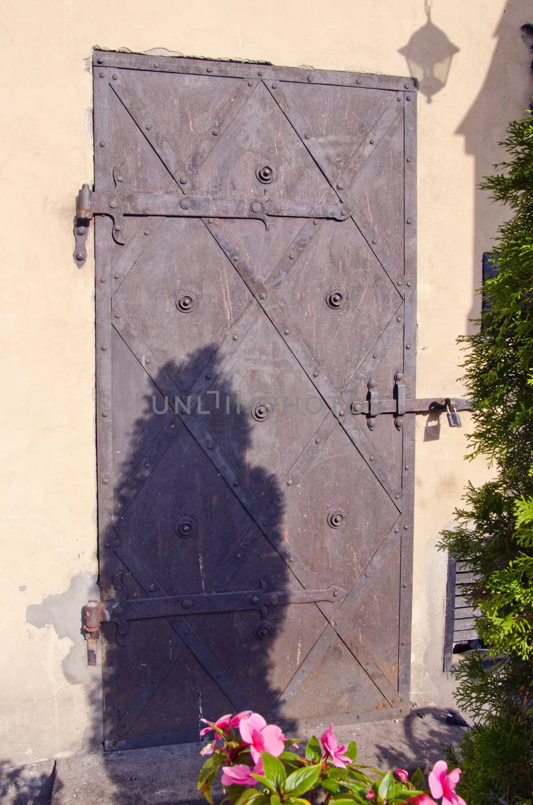 Ancient metal door with locked padlock ornament. by sauletas