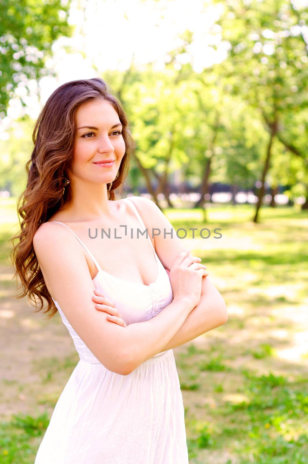 Portrait of an attractive woman in the park, crossed her arms and smile