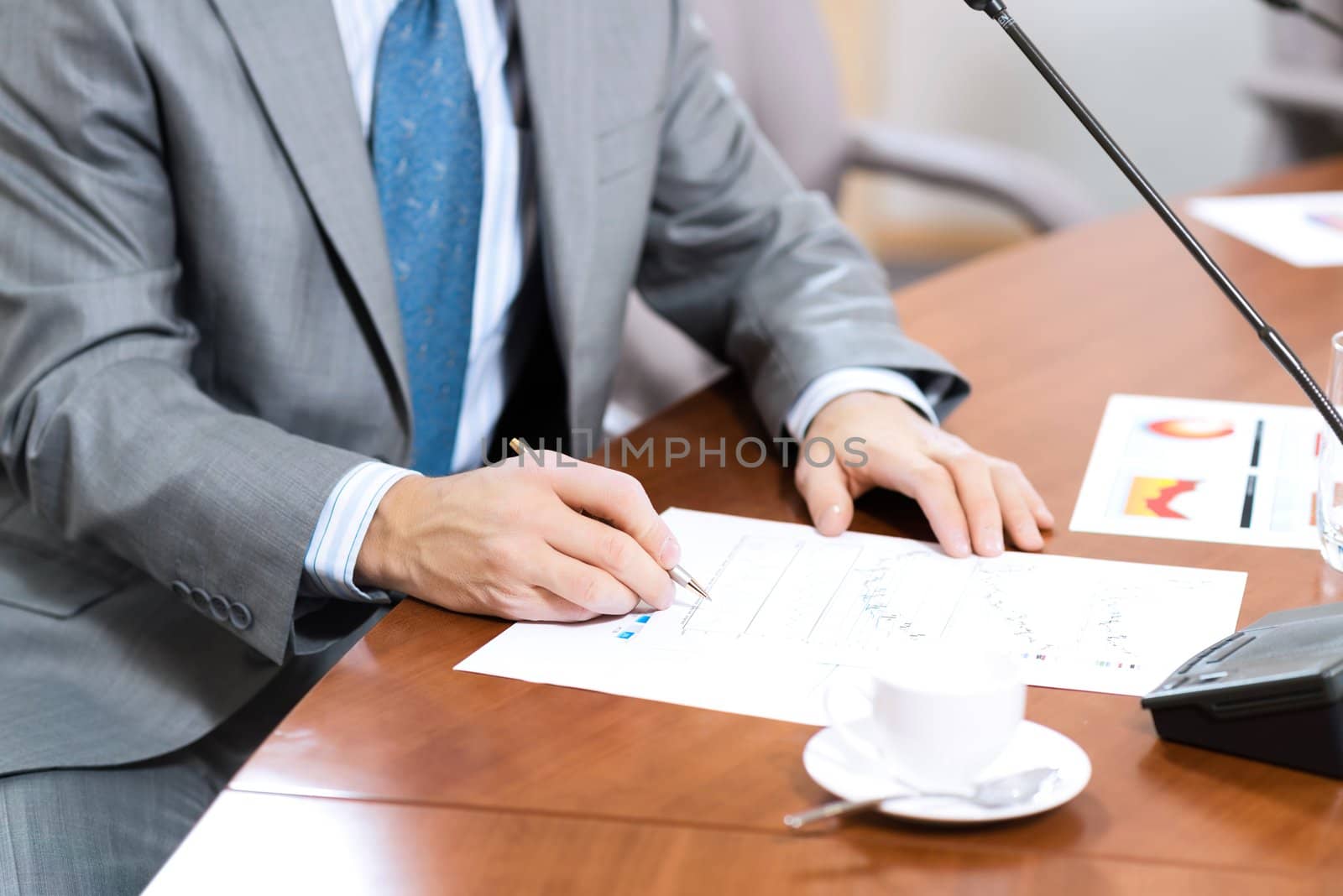businessman taking notes, meeting businessmen at the table there are microphones and decomposition of business documents