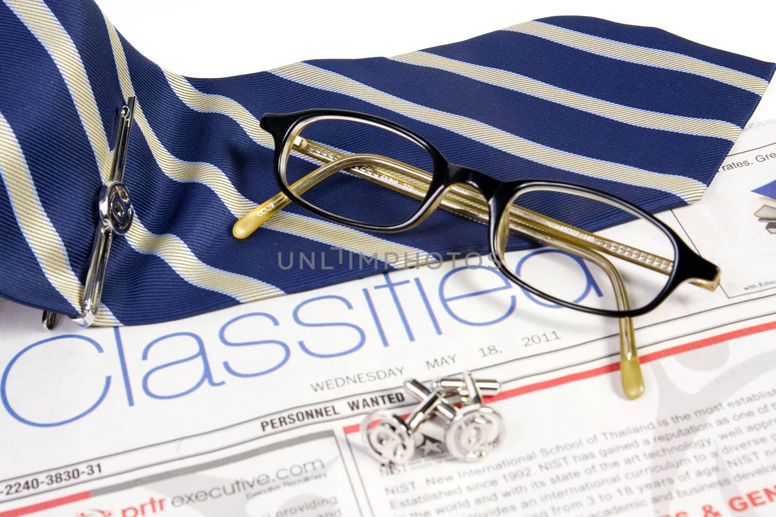 Jobs classified market on newspaper with ties tieclip cufflinks and glasses